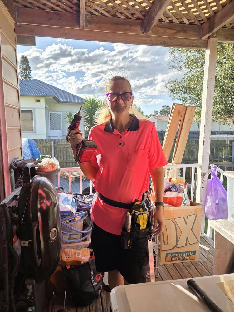 A woman with a cordless drill and tool belt, ready for jobs around the home